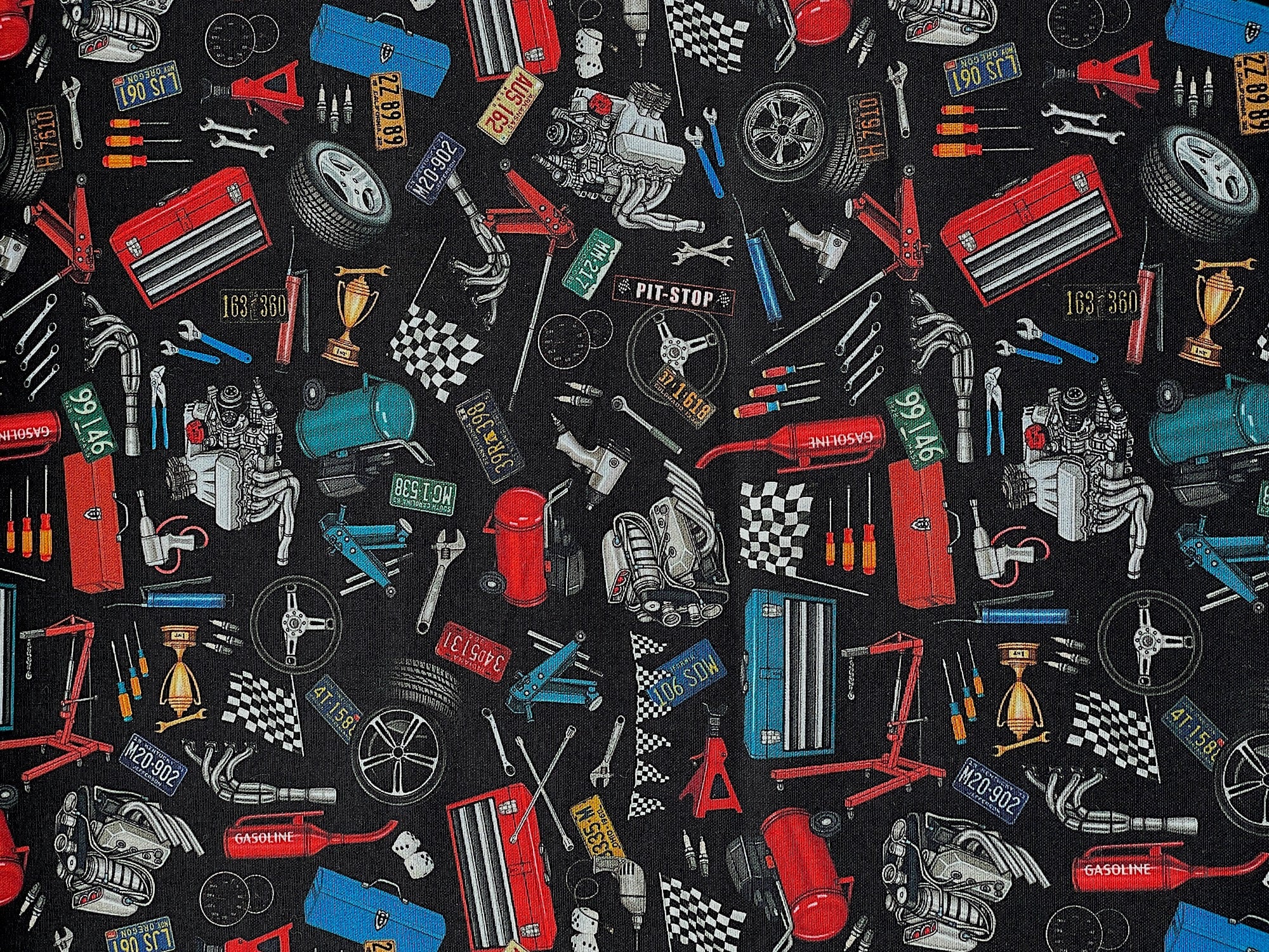 This black cotton fabric is covered with car parts and tools. You will find tool boxes, air compressor, motors, wheels, flags, license plates, pliers and more.