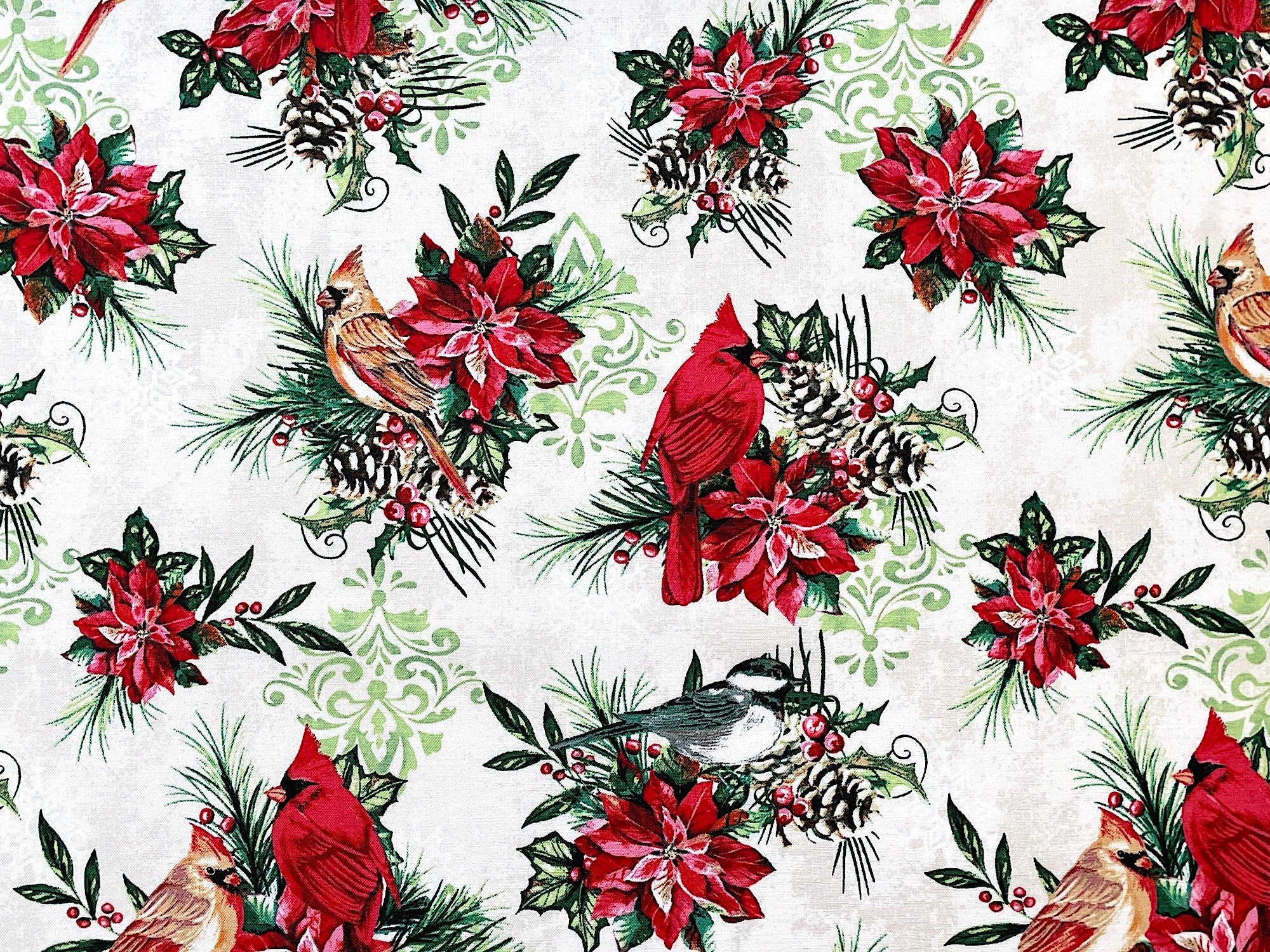 This fabric is part of the Holiday Greetings collection by Jean Plout. This Ivory colored fabric is covered with red cardinals sitting on branches made up of leaves, pine cones, poinsettias and leaves