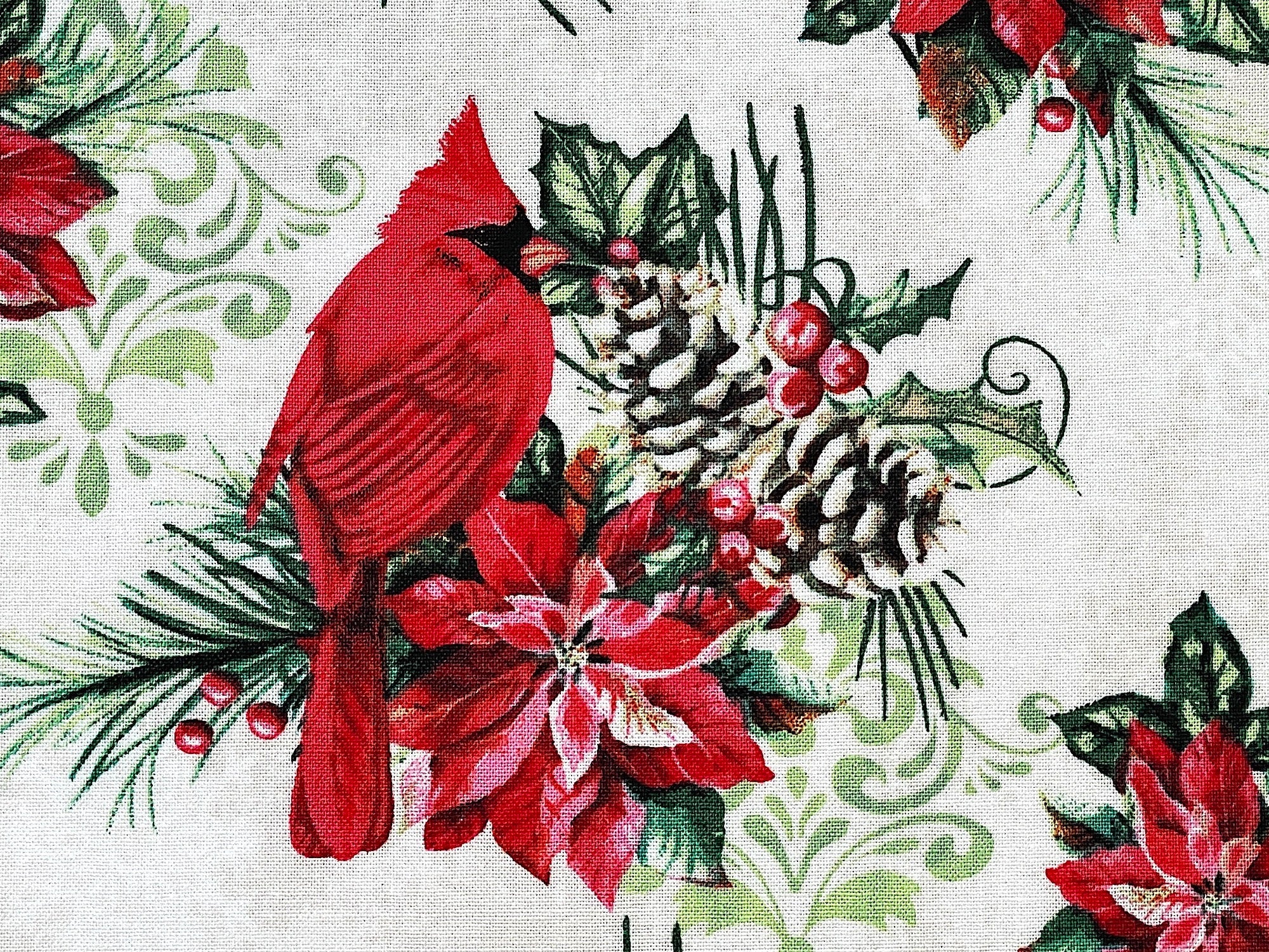 Close up of a red cardinal sitting on a branch with a poinsettia, pine cones, berries and more.