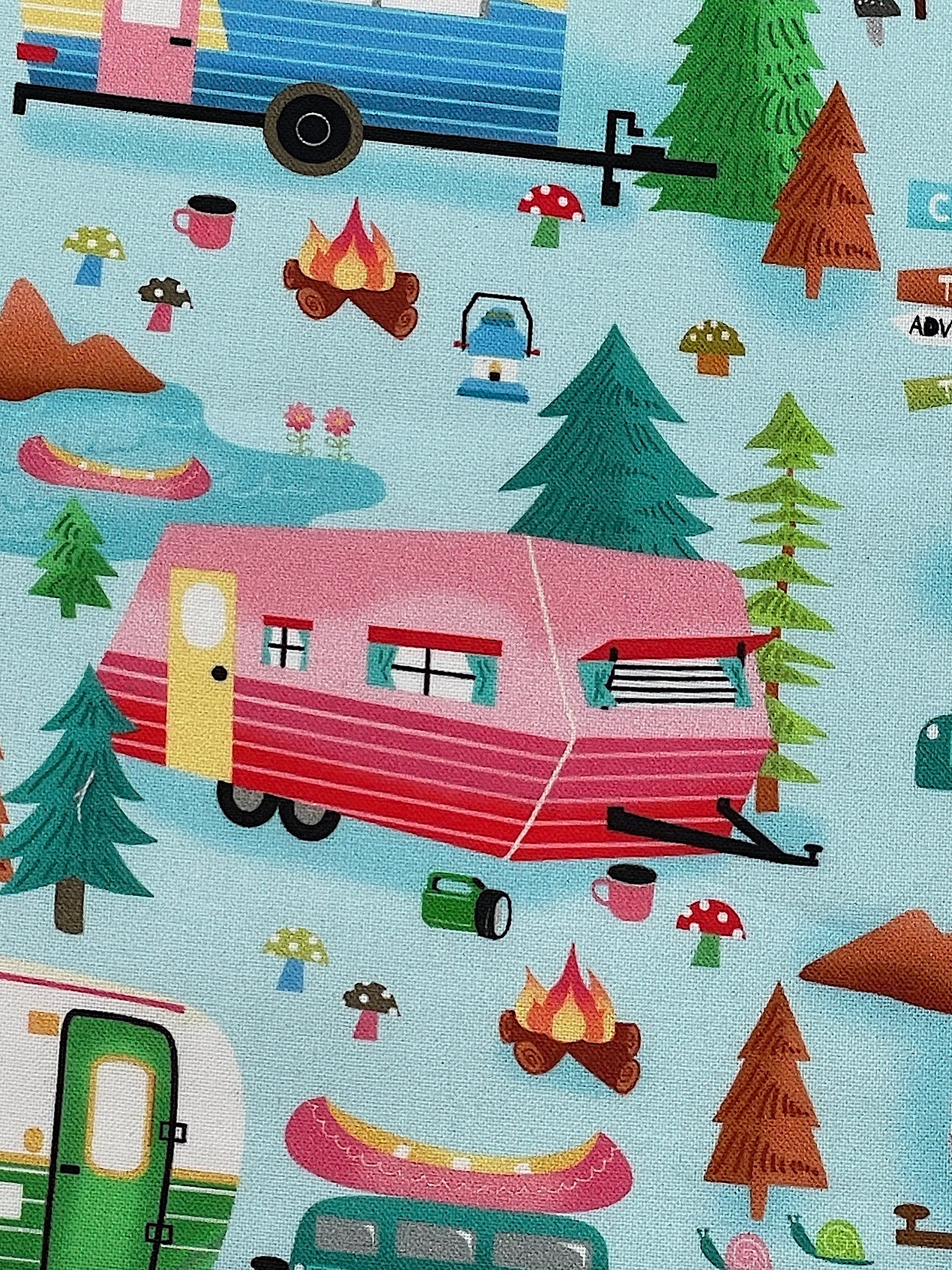 Close up of a pink and red travel trailer, trees, fire pit and more.