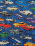 This blue cotton fabric is covered with old cars. The cars are white, green, blue, purple, blue, orange and black.