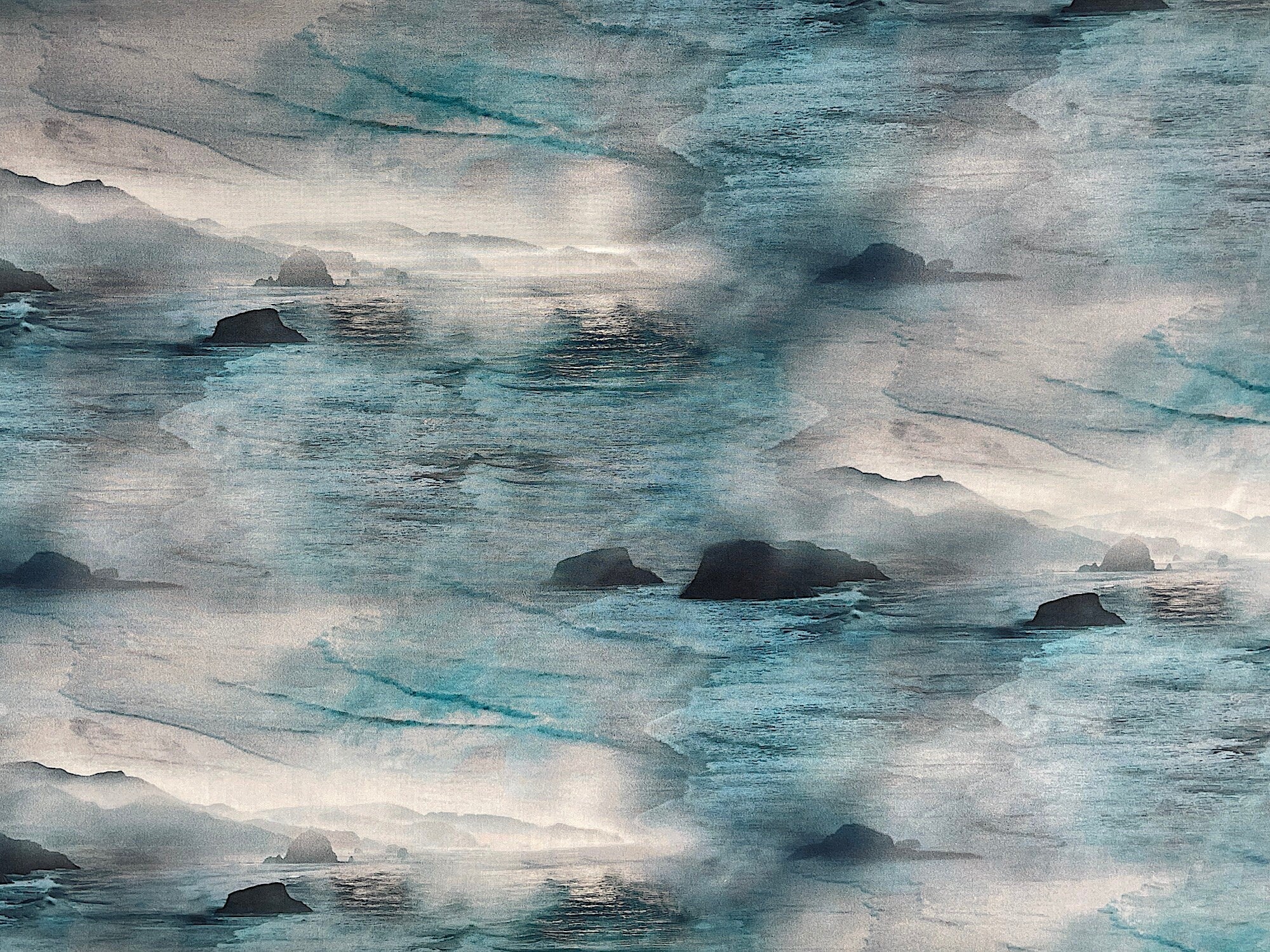 This fabric is called Sea Salt Focal Canon Beach Ocean. This fabric is like you are looking at the ocean as its covered with large rocks, mountains, water and waves. You will find shades of teal, blue and white along with black rocks.
