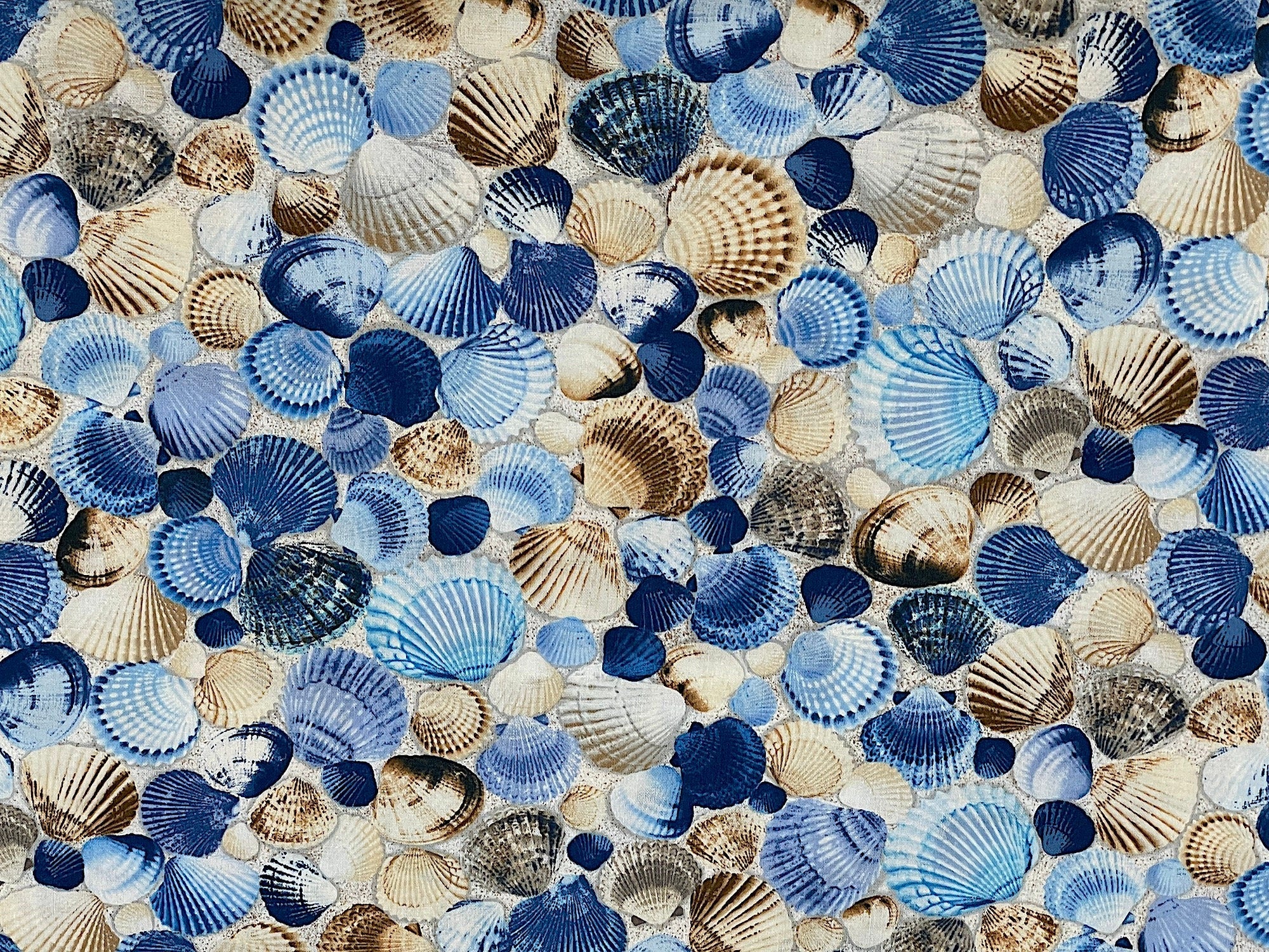 This cotton fabric is covered with seashells that are shades of blue and beige.