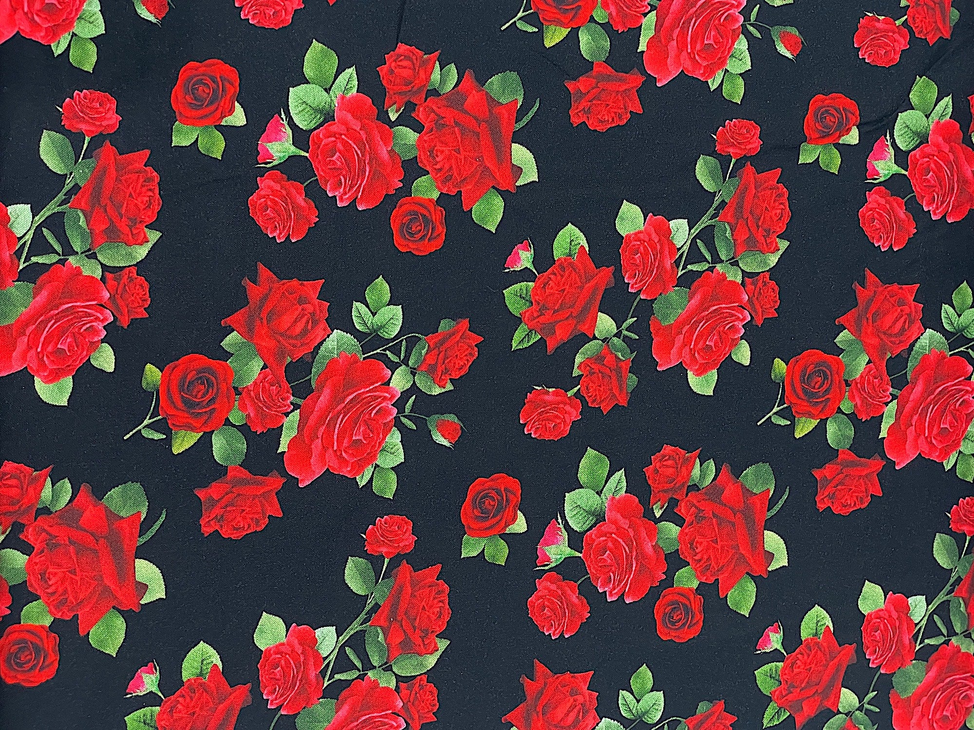 Black cotton fabric covered with red roses and green stems and leaves.